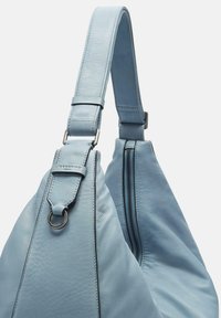 Jasnoniebieska skórzana torebka o gładkiej fakturze, z szerokim paskiem, srebrnymi elementami i zasuwaną kieszonką boczną dla większej wygody.