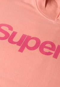 Roze hoodie met grote, gedurfde, fuchsia "Super" tekst op een zachte, gestructureerde stof. Het ontwerp heeft een capuchon en ribgebreide randen.