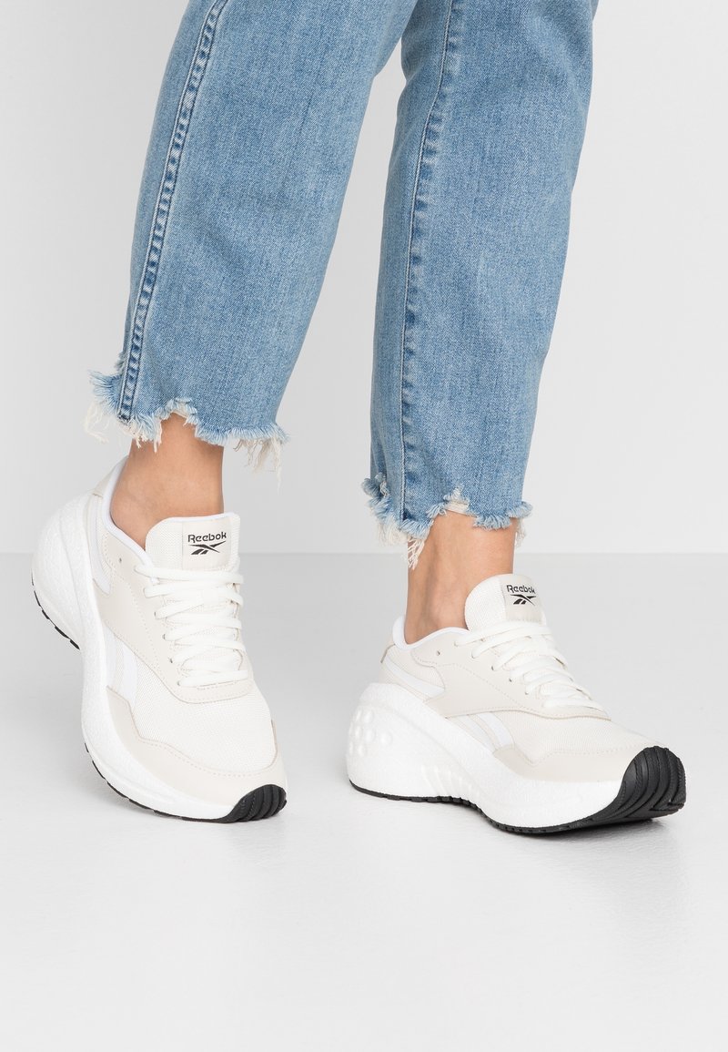 Vitaidrottsskor med texturerat mesh och slät läder. Har en tjock, vadderad sula och svart gummisula. Stilig kombination med fransiga jeans.