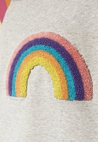 Szary materiał z teksturowaną, wielokolorową tęczową łatą. Kolory obejmują różowy, fioletowy, żółty, pomarańczowy i niebieski w kształcie łuku.