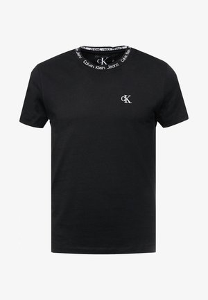 T-shirt noir à manches courtes avec logo "cK" blanc sur la poitrine et texte "Calvin Klein Jeans" autour du col intérieur.