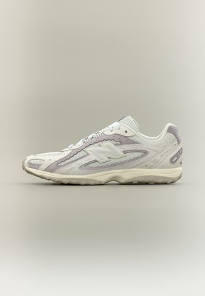 Witte en lichtgrijze New Balance sneaker met mesh en suède bovenkant, gevoerde zool en veterontwerp, weergegeven in zijprofiel.