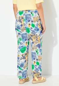 Gepatternde broek in een lichtblauwe stof met verschillende illustraties in groen, geel en marineblauw, die historische en natuurthema's laten zien.