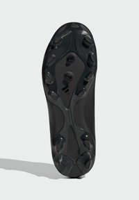 Suela de botas de fútbol negras con una superficie texturizada, múltiples tacos para tracción y un diseño aerodinámico con elementos de marca sutiles.