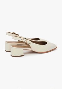 Beżowe skórzane buty slingback z ostrym noskiem i słupkowym obcasem. Posiadają boczny zamek i wycięcia dla dodatkowego efektu.