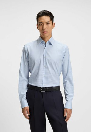 Hellblau karierter Hemd mit langen Ärmeln, knöpfbarem Kragen und schlanker Passform. Kombiniert mit dunklen Hosen und einem schwarzen Gürtel.