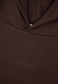 Sudadera marrón con material de mezcla de algodón, que presenta un bolsillo canguro y un pequeño detalle bordado que dice "Oh abril". Tejido texturizado.