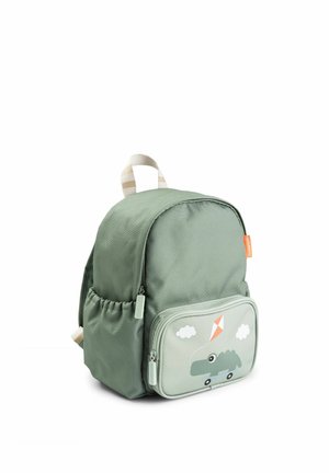 Kis zöld gyerek hátizsák első zsebbel, amelyen egy rajzfilm krokodil látható, amint görgőkön repülő drónt tart, valamint két fehér felhő.