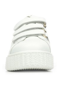 Witte sneaker met een gladde synthetische bovenkant, drie klittenbandsluitingen en een getextureerde rubberen zool. Accentkleur is goudkleurige hardware.