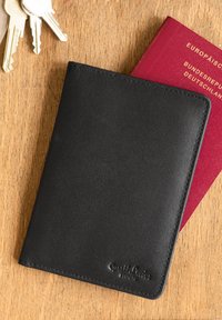 Mustast nahast passikott, millel on struktureeritud viimistlus, ääre õmblemine ja pressitud logo, koos punase passi ja võtmetega.