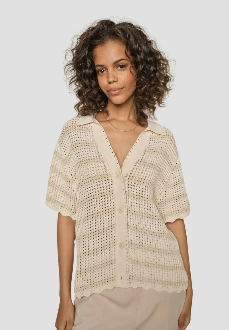 Light beige, short-sleeve knitted cardigan with a button-up front. Features a scalloped hem and textured open weave design.