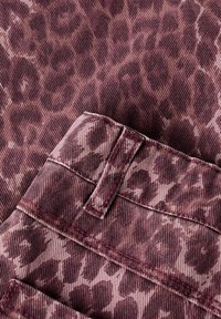 Tuvas tuvplāna purpura džinsa audums ar tumšo leopardu rakstu, dubultšuvēm un jostas cilpas detaļu.