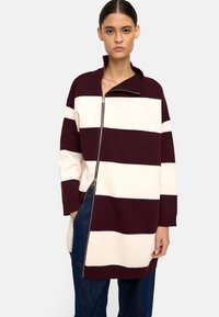 Bordowy sweter w kremowe paski z wysokim kołnierzem i pełnym zamkiem, wykonany z miękkiego dzianiny, z długimi rękawami i bocznymi kieszeniami.