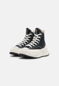 Zwart canvas hoge sneakers met witte veters en stiksels. Voorzien van een chunky witte tussenzool en een gestructureerde zwarte rubberen buitenzool.