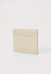 Béžový kožený držák na karty se čtyřmi sloty na karty, embosovaným logem a kontrastním prošíváním. Minimalistický design s hladkým povrchem.
