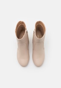 Krémové kotníkové boty, hladká kůže s kulatou špičkou a bočním zipem. Minimalistický design, s jednoduchým prošitím a měkkou vnitřní podšívkou.