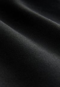 Tissu noir lisse avec des plis subtils et une texture fine sous un éclairage doux.