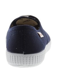 Scarpa slip-on in tela blu navy con suola in gomma bianca vista da dietro, che mostra le cuciture e un piccolo cartellino del marchio in tessuto sul lato.