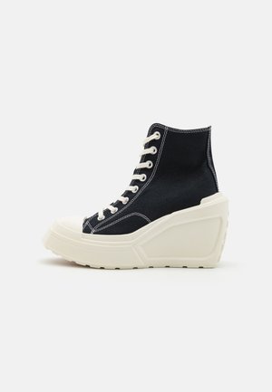 Sneakers alte realizzate in tela nera con cuciture bianche, suola a cuneo bianca e punta rinforzata. Presentano un classico design con lacci.