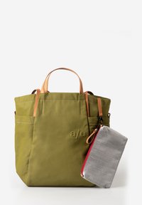 Olive green tote bag with tan leather handles, exterior pockets, and a detachable light gray zippered pouch with red trim hanging on one side.