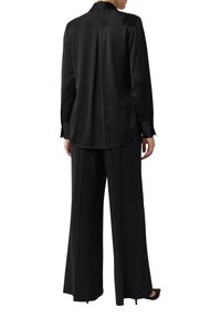 Black silk long-sleeve shirt with a back pleat, paired with wide-leg black trousers, featuring a smooth texture and classic collar design.