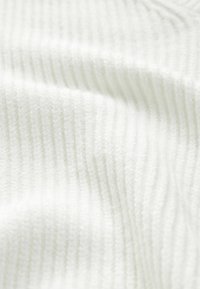 Vitt, ribbat textil med en mjuk, texturerad yta som har fina vertikala linjer. Materialet ser ut att vara plyschigt och lätt.