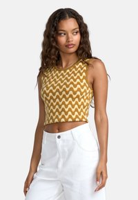 Brun og beige bølge-mønstrede strikkede cropped tanktop med rund halsudskæring, parret med højtaljede hvide bukser.