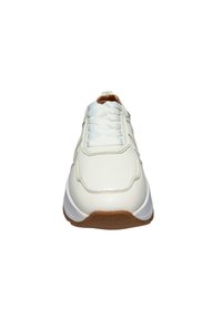 Scarpa da ginnastica bianca con tomaia in pelle liscia, lacci lavorati e suola in gomma marrone. Design curvo con sottili accenti di cuciture.