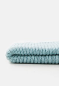 Light blue knitted fabric folded neatly on a white surface, showing ribbed texture and soft fibers.