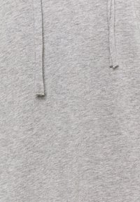 Gray cotton fabric with a subtle texture, featuring a drawstring detail at the top. The surface appears soft and slightly heathered.