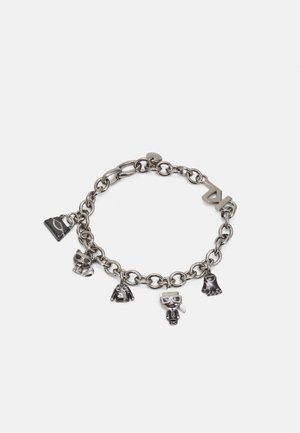 Bracelet chaîne en argent avec six breloques : sac à main, chat avec des lunettes de soleil, veste, personnage avec des lunettes et une queue de cheval, patte, et logo double "K".