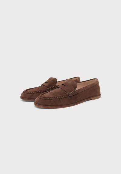 Paire de mocassins penny en suède marron avec des détails cousus et semelles plates sur un fond clair uni.