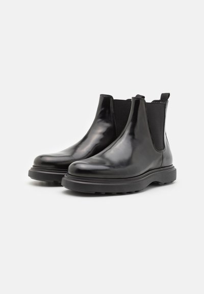 Botas Chelsea de cuero negro con un diseño estilizado, paneles laterales elásticos y una suela de goma texturizada para mayor agarre. Acabado suave y construcción robusta.