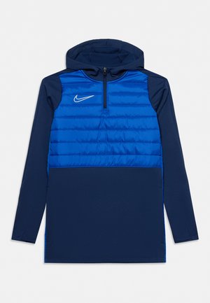 Haut Nike à enfiler, bleu marine et bleu vif, avec capuche, courte fermeture éclair sur le devant, manches longues et empiècements matelassés sur la poitrine.