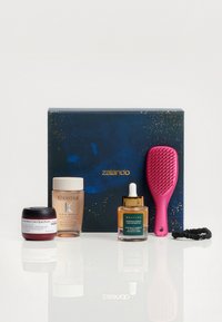 Presentförpackning i marinblått med gyllene detaljer innehåller: mörk burk, klar flaska, amberolja, rosa hårborste och svart hårsnod. 