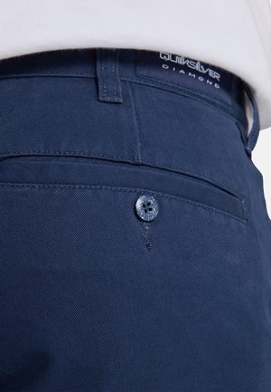 Navy blue pants made of smooth fabric, featuring a back pocket with a blue button and visible stitching details, labeled "Quiksilver Diamond."