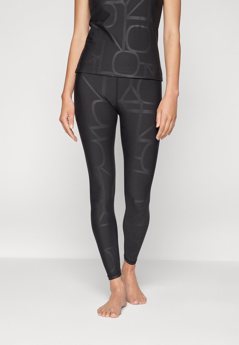 Schwarze Sportleggings und passendes Oberteil mit einem dezenten, einfarbigen Logo-Muster. Hergestellt aus einem dehnbaren, glatten Material für mehr Komfort.