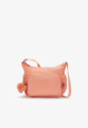 Peach-colored crossbody bag made of textured nylon, featuring a front zipper pocket, logo patch, and a furry pom-pom charm attached.