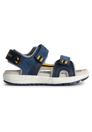Sandalias sintéticas azules con correas ajustables y acentos amarillos. Plantilla texturizada en gris y suela de goma blanca con patrón antideslizante.