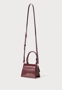 Sac à main en cuir verni bordeaux avec une forme triangulaire structurée, double poignée supérieure et une bandoulière réglable. Accents en métal doré.