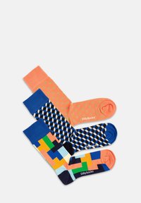 Drei Paar Socken: eine korallenrote mit goldenen Punkten, eine marineblaue mit geometrischem Muster und eine mit einem mehrfarbigen abstrakten Design, alle mit kontrastierenden Bündchen.