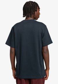 Mørkebl�å kortærmet t-shirt med afslappet pasform, rund halsudskæring og blødt bomuldsstof. Minimalistisk design, ingen synlige mønstre eller grafikker.