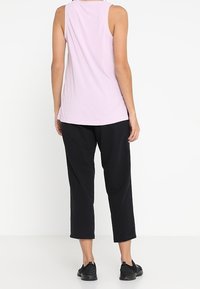 Ljuslila ribbad linne med avslappnad passform, matchad med svarta cropped byxor och svarta slip-on skor, sedd bakifrån.