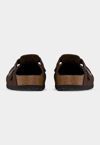 Ζευγάρι καφέ μοκασίνια Birkenstock με μαύρες σόλες, προβολή από πίσω σε λευκό φόντο.