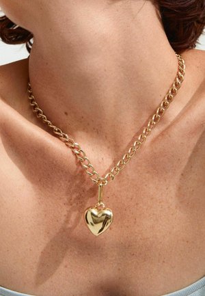 Collana in oro con pendente a forma di cuore grande e lucido. La catena presenta un design a maglie e una finitura liscia e lucida.