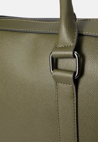 Bolso de mano de cuero texturizado verde con un acabado suave, que cuenta con una cremallera segura y detalles metálicos para mayor durabilidad.