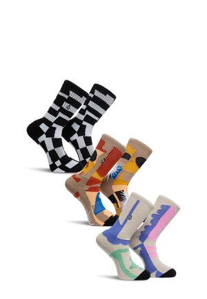 Cinq paires de chaussettes montantes colorées à motifs, exposées verticalement, incluant un motif à carreaux noir et blanc, des motifs abstraits orange et jaune, ainsi que des motifs pastel bleu et rose.