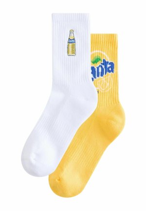 Weiße und gelbe Crew-Socken; die weiße Socke hat ein kleines blaues und gelbes Fanta-Flaschenlogo, während die gelbe Socke die Fanta-Branding in Blau und Grün trägt.