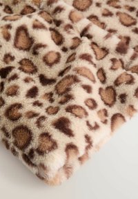 Un material moale, pufos, cu un fundal bej deschis și pete neregulate de leopard maronii, arătând textură și cute.