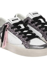 Sneakers bianchi con lacci neri, dotate di un pannello laterale in glitter viola scintillante e una punta argentata. Include un etichetta rosa con il marchio.